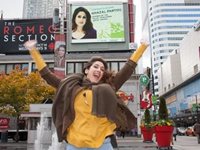 Artist Ghazal Partou jumps in front of her digital billboard in Dundas Square