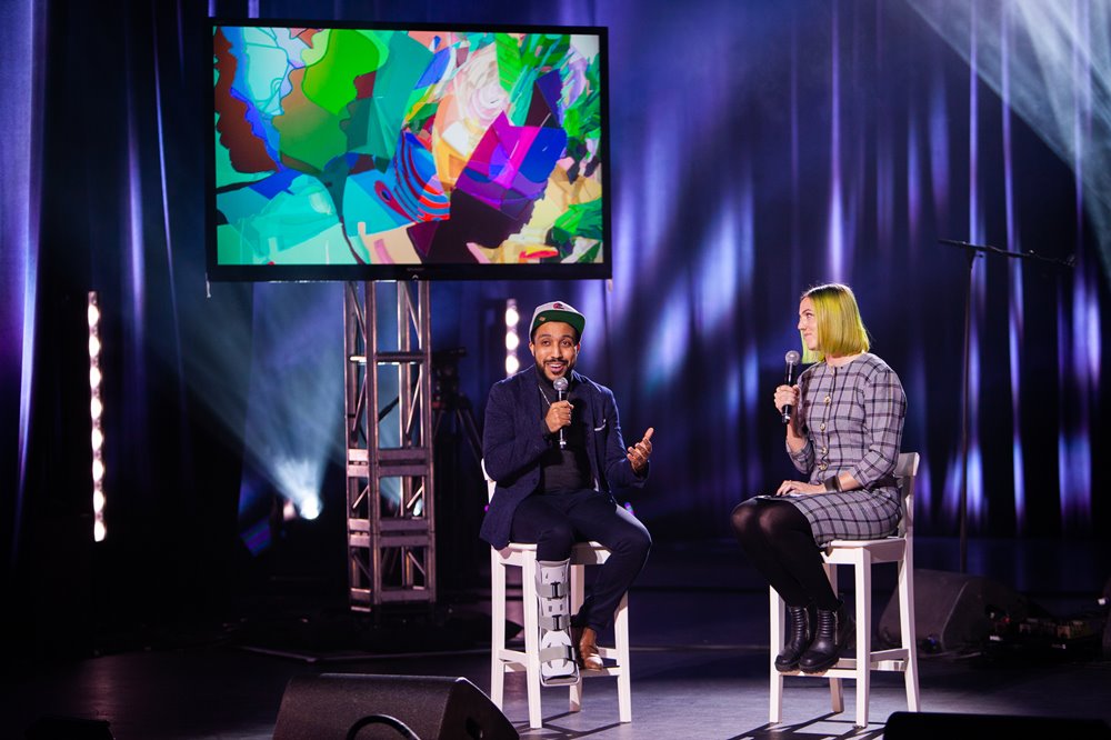 Luke Reece & Jennifer Alicia sit on chairs on stage