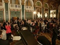 A room of people applaud a performer 