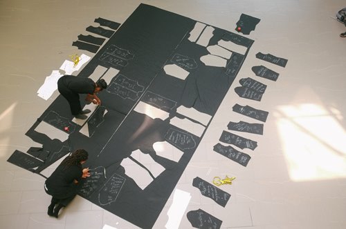 Two artists work on a large scale artwork on the ground