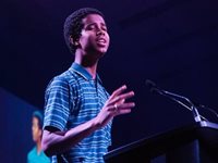 Poet Mustafa Ahmed speaks into a microphone