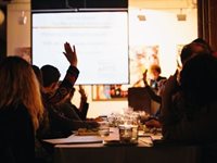 People sitting at a table raise their hands