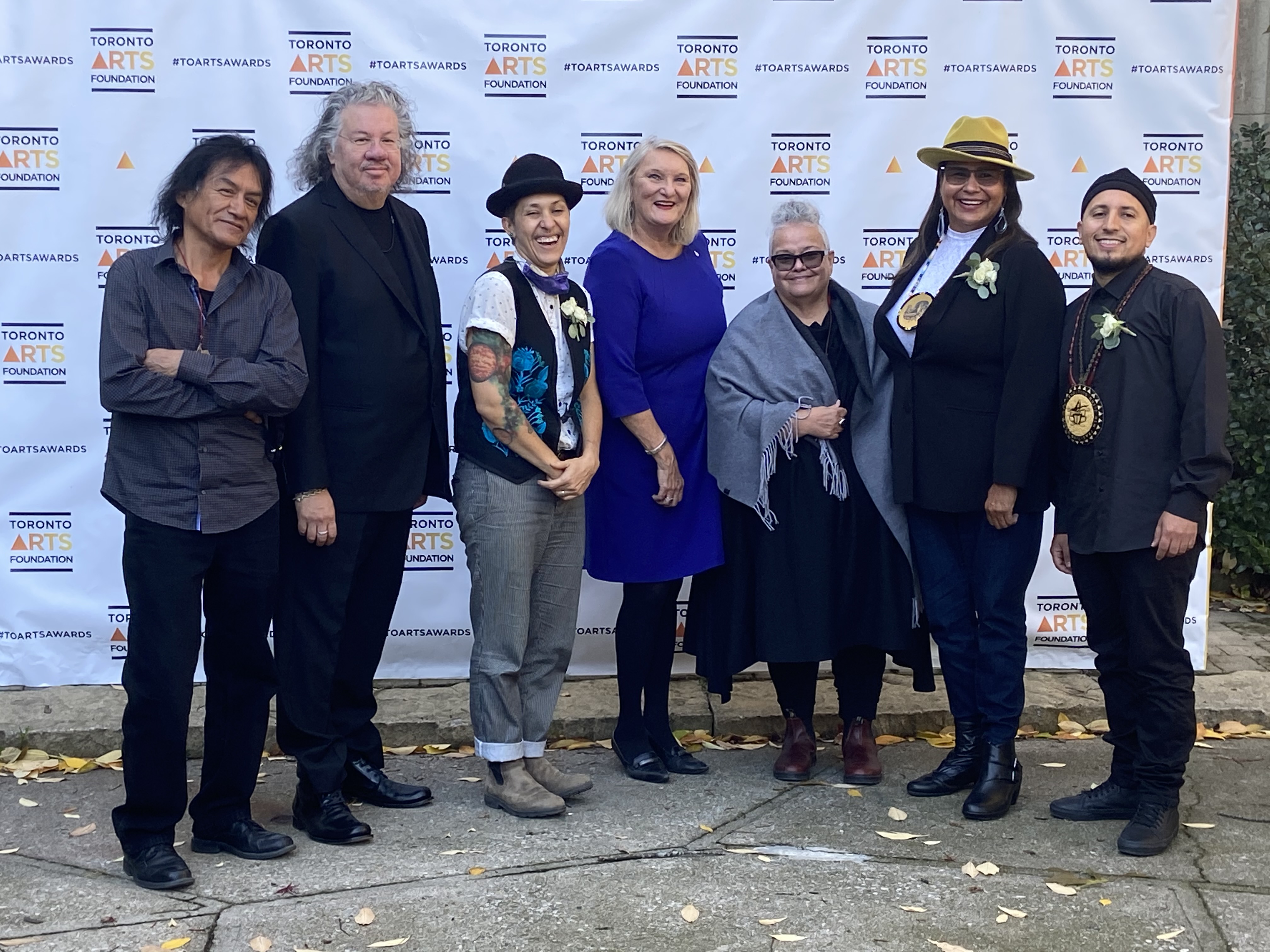 A picture of all the award finalists with Claire Hopkinson and Catherine Tammaro. They are standing in front of a Toronto Arts Foundation banner.