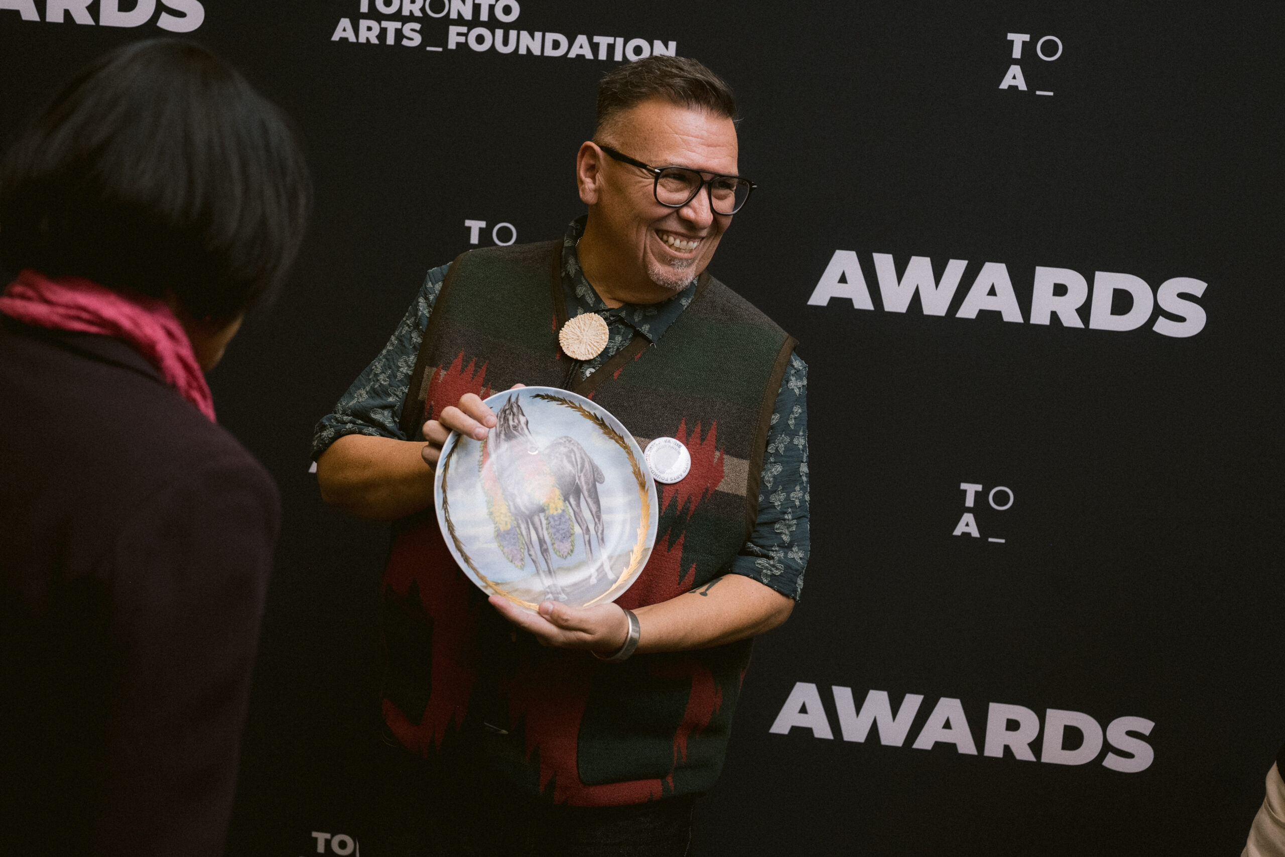 Ryan Rice holds an awards plate in front of a step-and-repeat.