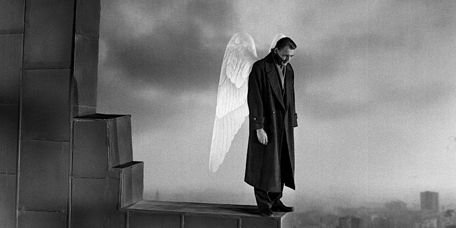 A man with angel wings stands with his head bowed.