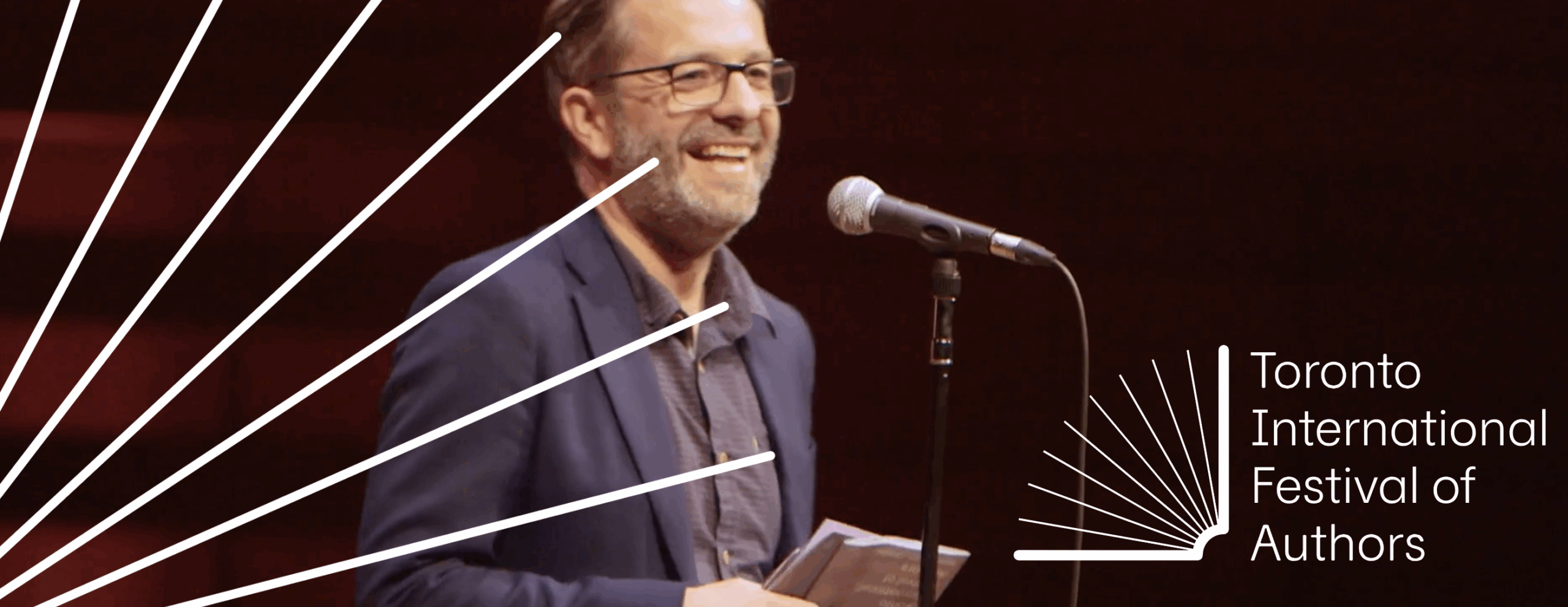 A man stands at a lectern, smiling.