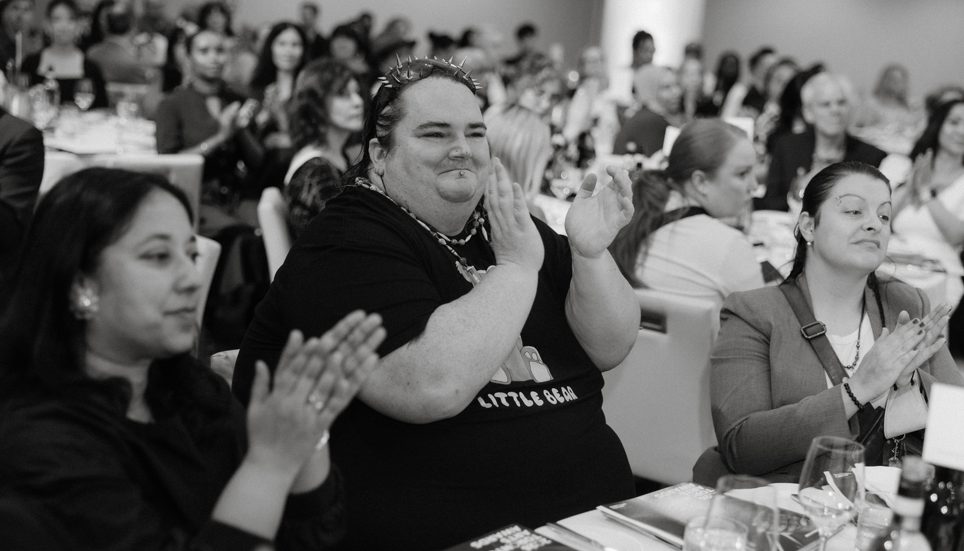 Rainbow Hunt applauds while seated at a table at the 2026 Mayor's Arts Lunch.