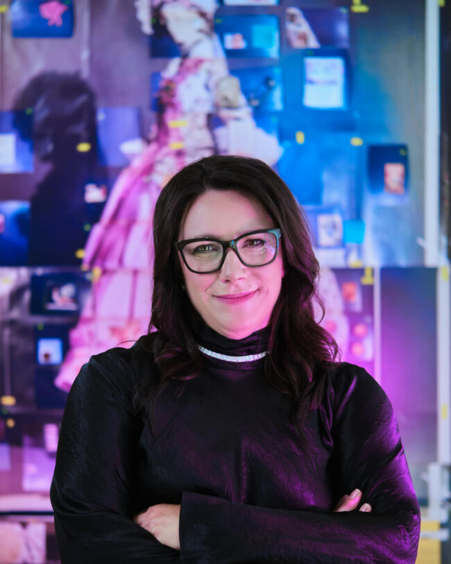 Heather Jessiman stands in front of a colourful background.