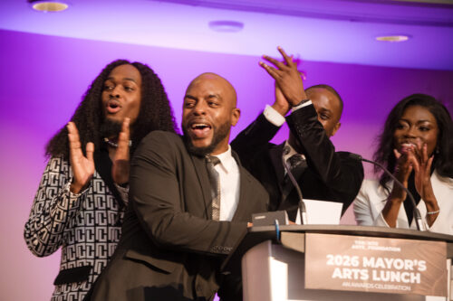 People applaud at a podium. A sign on the podium reads: 2026 Mayor's Arts Lunch