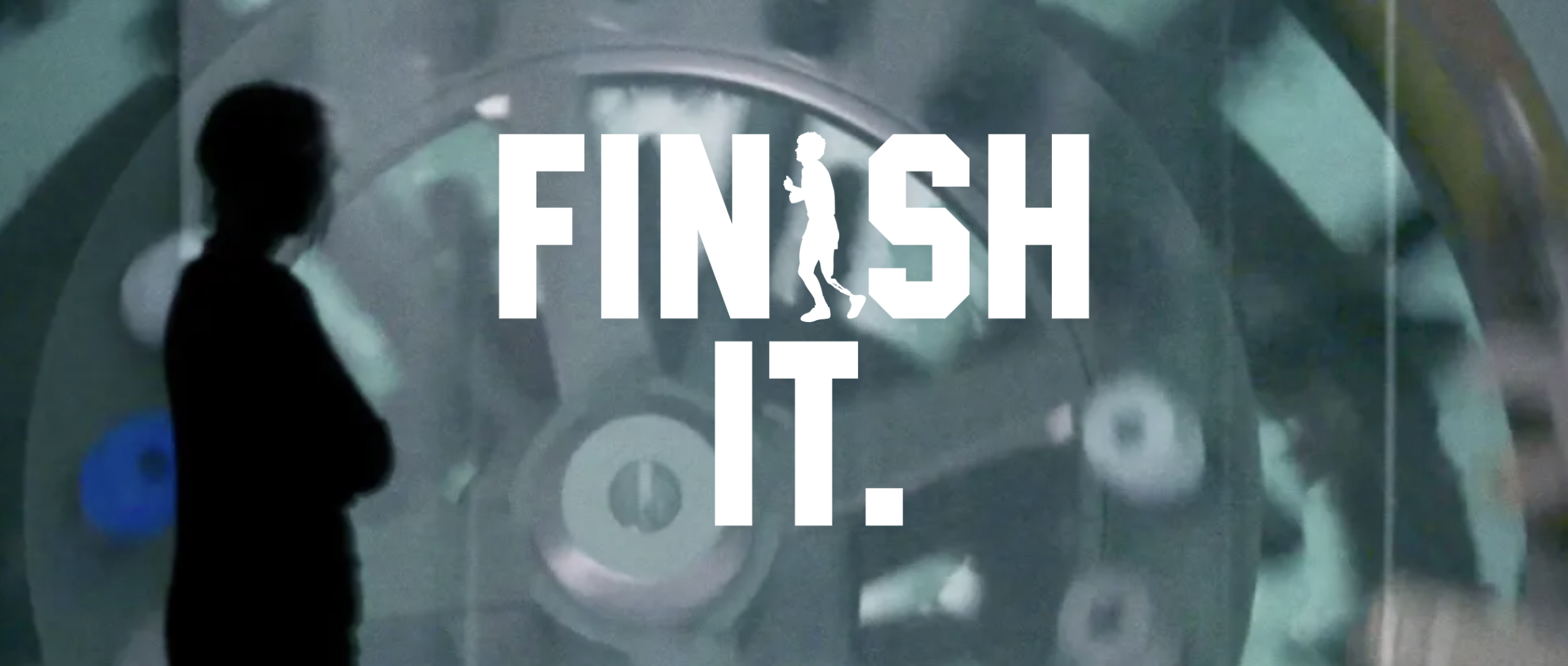 A person stands in front of a burry projection. Text reads: FINISH IT.